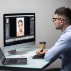 Side view of a casual male photo editor using graphics tablet in a bright office