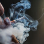 a closeup shot of a person puffing on a cigarette surrounded with smoke