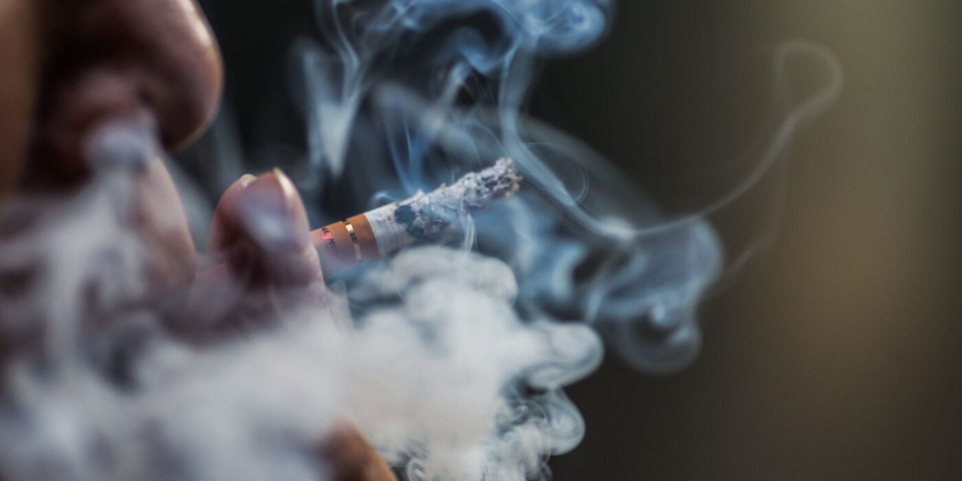 Closeup shot of a person puffing on a cigarette surrounded with smoke